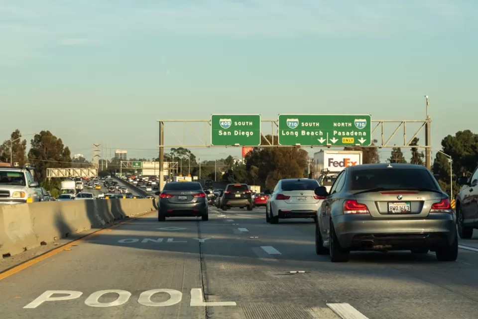 Smog hovers in the air in the background of this image of heavy car traffic on the 405 Freeway near ints intersection with the 710 Freeway in Southern California.